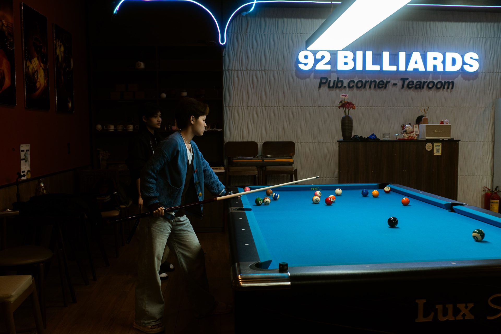 A regular lining up a shot beneath the 92 Billiards sign
